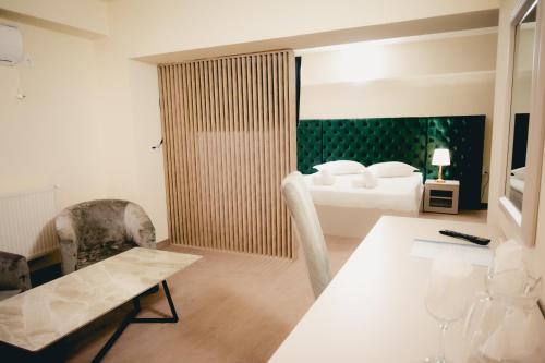トゥルゴヴィシュテにあるHotel Valahiaのベッド、テーブル、椅子が備わるホテルルームです。