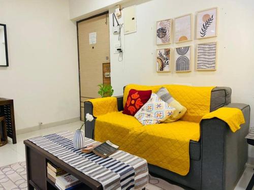 a yellow couch in a living room with a table at Marina 203, NL Road, Bandra West by Connekt Homes in Mumbai