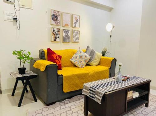 a living room with a yellow couch and a table at Marina 203, NL Road, Bandra West by Connekt Homes in Mumbai