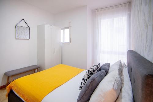 ein Schlafzimmer mit einem Bett mit einer gelben Decke in der Unterkunft Apartamento A pie de Playa in Miño
