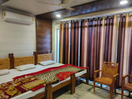 a bedroom with a bed and two chairs and a window at Hotel Shubhadra Guest House in Mathura