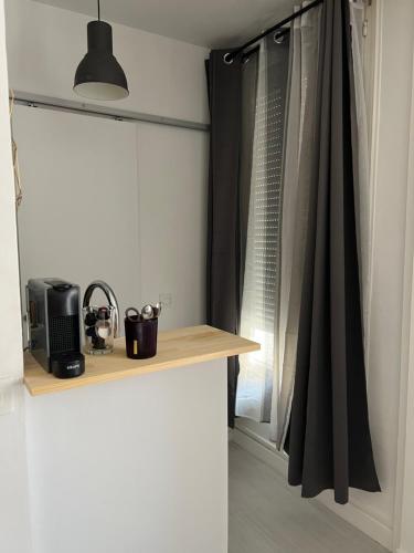 une cuisine avec un comptoir avec une fenêtre avec des rideaux noirs dans l'établissement Studio moderne tout confort, à Champigny-sur-Marne