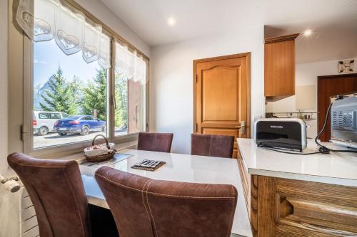 une cuisine avec une table et des chaises et une fenêtre dans l'établissement Au rêve savoyard 2 - 4 personnes, à Morillon