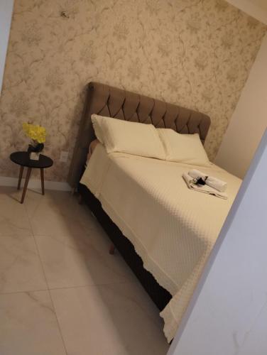 1 dormitorio con 1 cama y mesa auxiliar en Apartamento novo Gran Safira, en Itapema