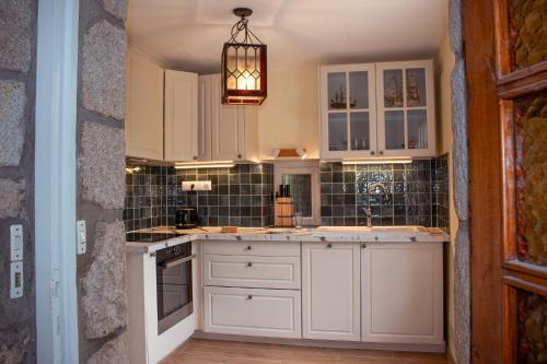 een keuken met witte kasten en een kroonluchter bij Maison vue sur les alignements de Carnac - Les Glycines in Carnac