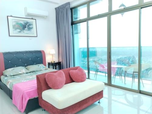 a bedroom with a bed and a couch and a balcony at Palazio AegeanSea Homestay By Easyhomestay in Johor Bahru