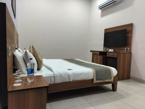 a bedroom with a bed with a television and a table at Sun Hotel and Resort, Mount Abu in Ābu Road