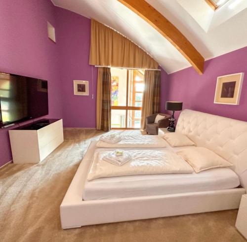 a bedroom with a white bed and purple walls at Lipno Holiday Penthouse in Lipno nad Vltavou