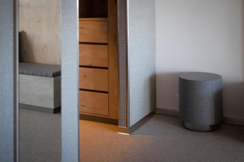 two pictures of a room with a stool and a cabinet at Victoria Hotel & Residence in Villars-sur-Ollon