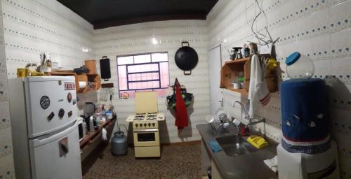 a small kitchen with a stove and a refrigerator at Casa Indaiá BnB - casa compartilhada in Caraguatatuba