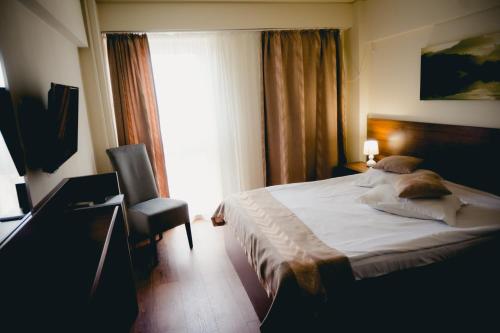 a bedroom with a bed and a chair and a window at Hotel Valahia in Târgovişte