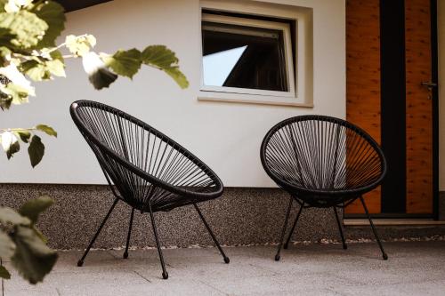 two black chairs sitting in front of a building at Holiday House Sunset Spa in Šentjernej