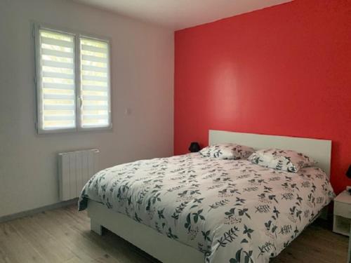 1 dormitorio con cama y pared roja en Les Enfants du Marais, en Favières