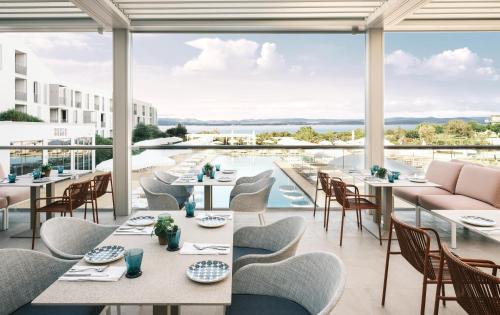 a restaurant with tables and chairs and a pool at Falkensteiner Family Hotel Diadora in Zadar