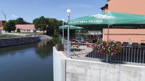 a restaurant with a green umbrella next to a river at Ankerhof Hotel in Halle an der Saale