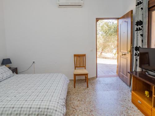 Schlafzimmer mit einem Bett, einem TV und einem Stuhl in der Unterkunft Cubo's Casa Pedroche Hacienda El Encinar in Villaharta