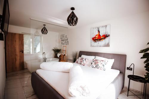 a bedroom with a white bed and a bathroom at Holiday House Sunset Spa in Šentjernej