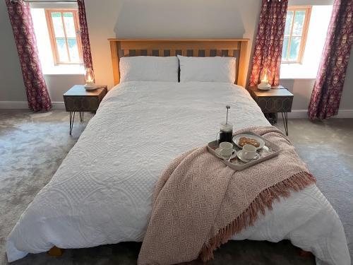 Un dormitorio con una cama grande y una bandeja de comida. en The Cottage at Sychnant Farm, en Talgarth