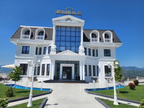 a large white building with a sign on top at Imperador Palace Hotel Restorant in Peshkopi