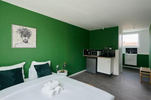 ein Schlafzimmer mit einer grünen Wand, einem Bett und einer Küche in der Unterkunft NG Prestige - Lille I Roubaix Jouffroy - Netflix - Wifi in Roubaix