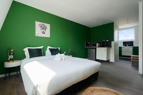- une chambre avec un grand lit blanc dans un mur vert dans l'établissement NG SuiteHome - Lille I Roubaix Jouffroy - Netflix - Wifi, à Roubaix