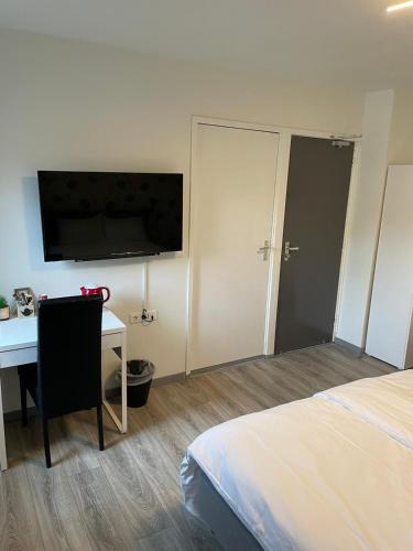 a bedroom with a bed and a desk and a television at Hotel B&B Sint-Maria NEXT DOOR in Valkenburg