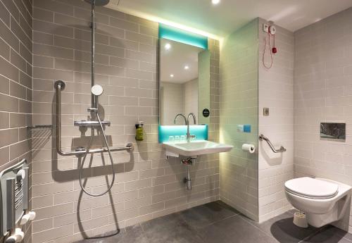 a bathroom with a shower and a toilet and a sink at B&B HOTEL Deauville-Touques in Deauville