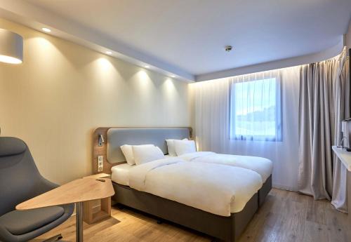 a hotel room with a large bed and a chair at B&B HOTEL Deauville-Touques in Deauville