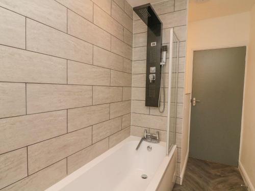 a bath tub in a bathroom with a tile wall at 2 Brook Street in Clitheroe