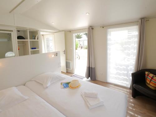 a white bed in a room with a large window at ULVF Les Beaupins in Saint-Denis-dʼOléron