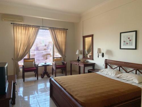 1 dormitorio con cama, escritorio y ventana en Nirwana Suites, en Denpasar