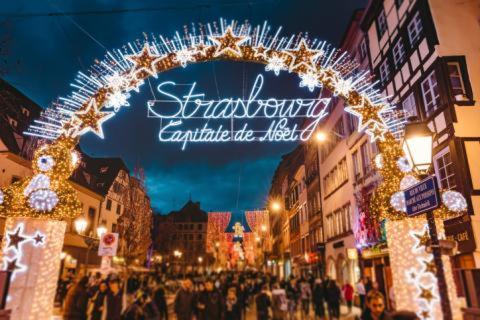 a crowd of people walking down a street with a lit up sign at Cozy Studio Strasbourg in Strasbourg