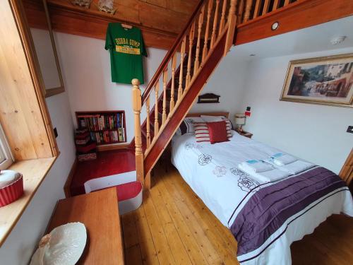 a bedroom with a bed and a stair case at F1 MAISON 108 - Holiday Home - Full Kitchen - Street FREE PARKING, NETFLIX - 68Mbps BT WIFI - DVD's - Welcome Tray - By Corner from Gavin n Stacey Film House in Barry