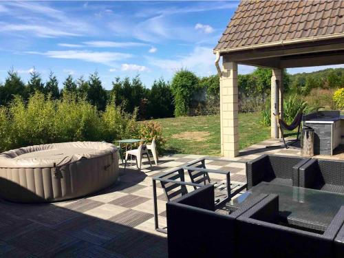 eine Terrasse mit einer großen Badewanne, einem Tisch und einem Grill in der Unterkunft Maison de 3 chambres avec jacuzzi jardin clos et wifi a Fretoy le Chateau 