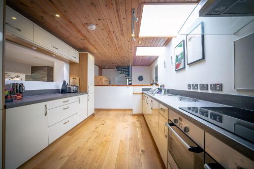 a large kitchen with white cabinets and a wooden ceiling at Kirkstone Lodge in Insh