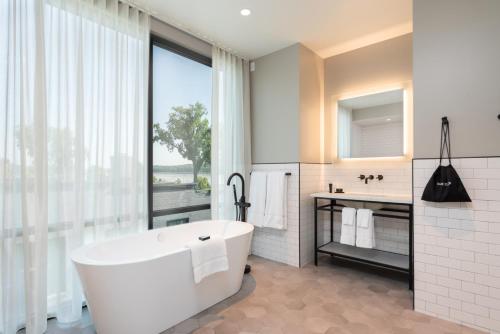 La salle de bains est pourvue d'une baignoire et d'une grande fenêtre. dans l'établissement voco James Newbury Hudson Valley, an IHG Hotel, à Coxsackie