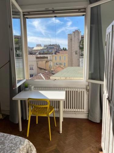 Cette chambre dispose d'une fenêtre avec une table et une chaise jaune. dans l'établissement Marseille Vieux Port, à Marseille