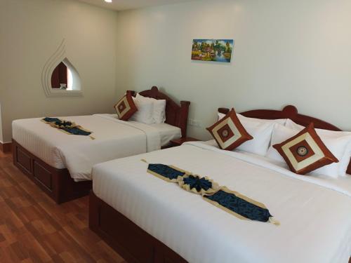 2 camas en una habitación de hotel con sábanas blancas en Sing Angkor Boutique Hotel, en Siem Reap