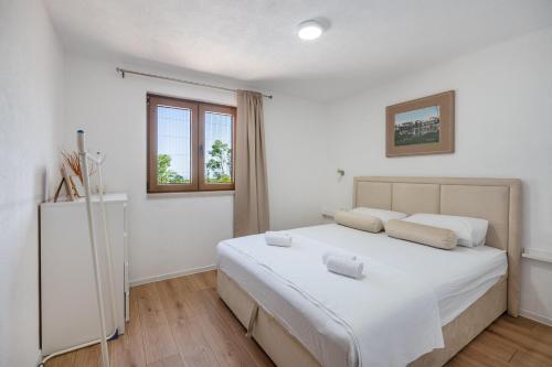 una camera da letto con un letto con lenzuola bianche e una finestra di Villa Ivanka a Neum