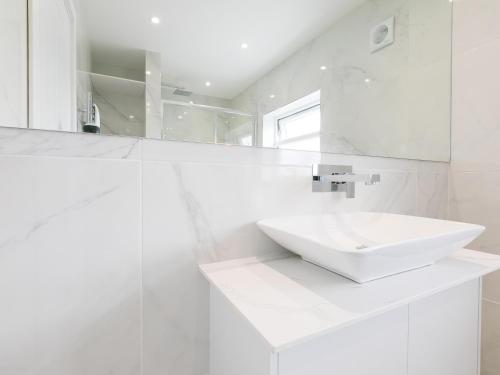 a white bathroom with a sink and a mirror at Samphire in St Ives