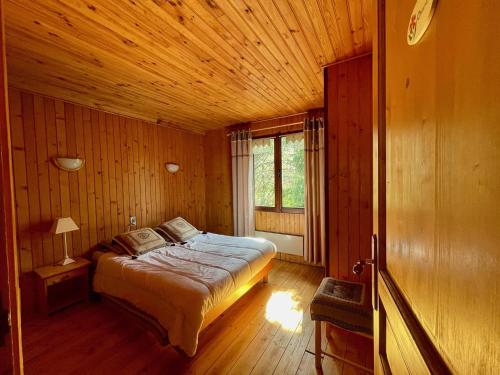 1 dormitorio con 1 cama en una habitación de madera en L'Ecrin des neiges, en Camprieu