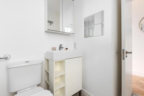 a white bathroom with a toilet and a sink at The Shepherd's Bush Luxury Villas in London