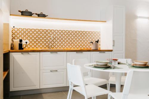 une cuisine avec des placards blancs et une table et des chaises blanches dans l'établissement Dal Monaco - casa vacanze, à Castellana Grotte
