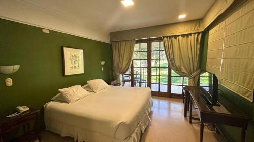 1 dormitorio con cama y pared verde en Hotel y Cabañas Huallilemu Sur - Caja Los Andes, en El Quisco