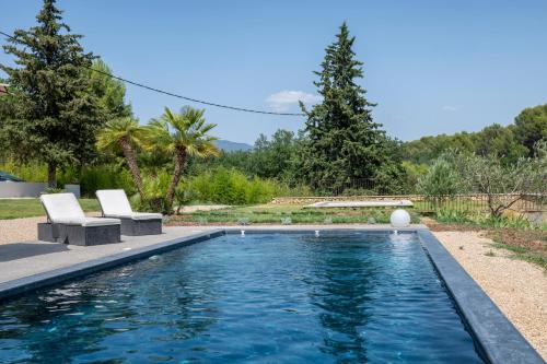 a swimming pool with two chairs in a yard at Villa Juliane in Cadenet