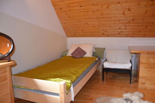 a small bedroom with a bed and a chair at Uroczy domek letniskowy. in Falsztyn