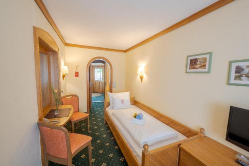 ein Hotelzimmer mit einem Bett und einem TV in der Unterkunft Chalét zum Kurfürst in Oberschleißheim