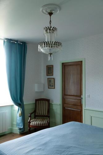 a bedroom with a bed and a chandelier and a chair at les chambres fleuries in Saint-Benoît-du-Sault
