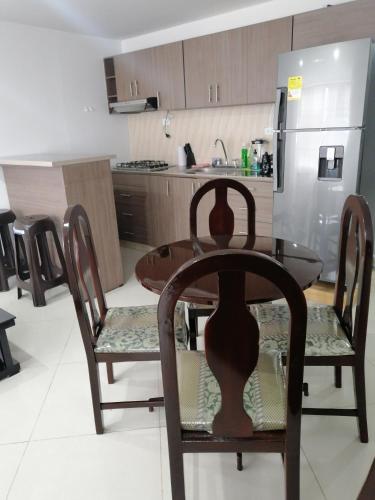 cocina con mesa, sillas y nevera en Moderno apartamento para huespedes en Ipiales