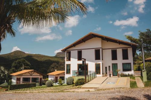 ein weißes Haus mit einer Palme in der Unterkunft Pousada Vale do Chapéu in Capitólio